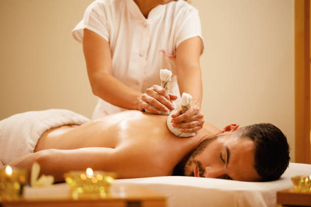 relaxed man enjoying in back massage with herbal compress during spa treatment.